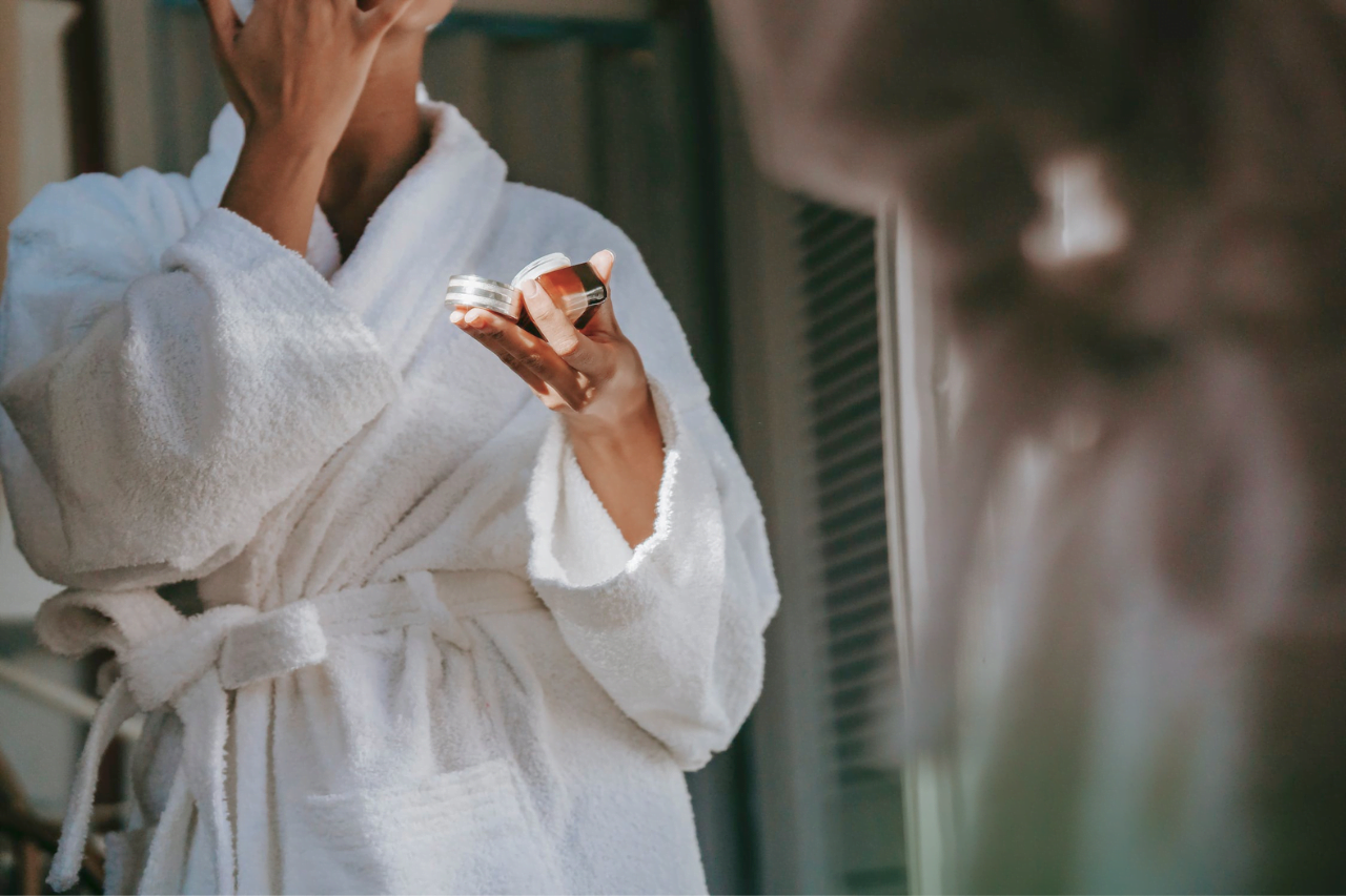 En kvinna i morgonrock som håller en burk med giftfri hudvård