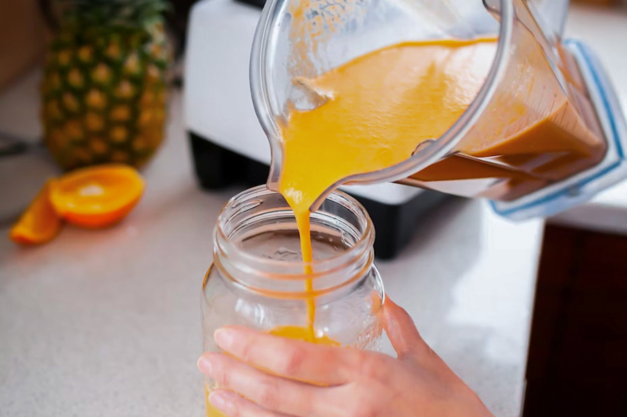 Upphällning av ananas och gurkmejasmoothie i ett glas