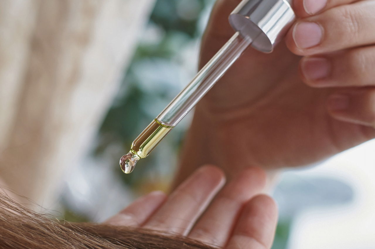 En pipett som droppar ut arganolja i handen för att smörja i håret för naturlig hudvård