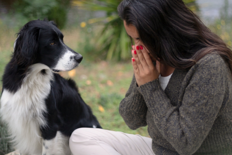 Kvinna med allergi nyser bredvid en hund
