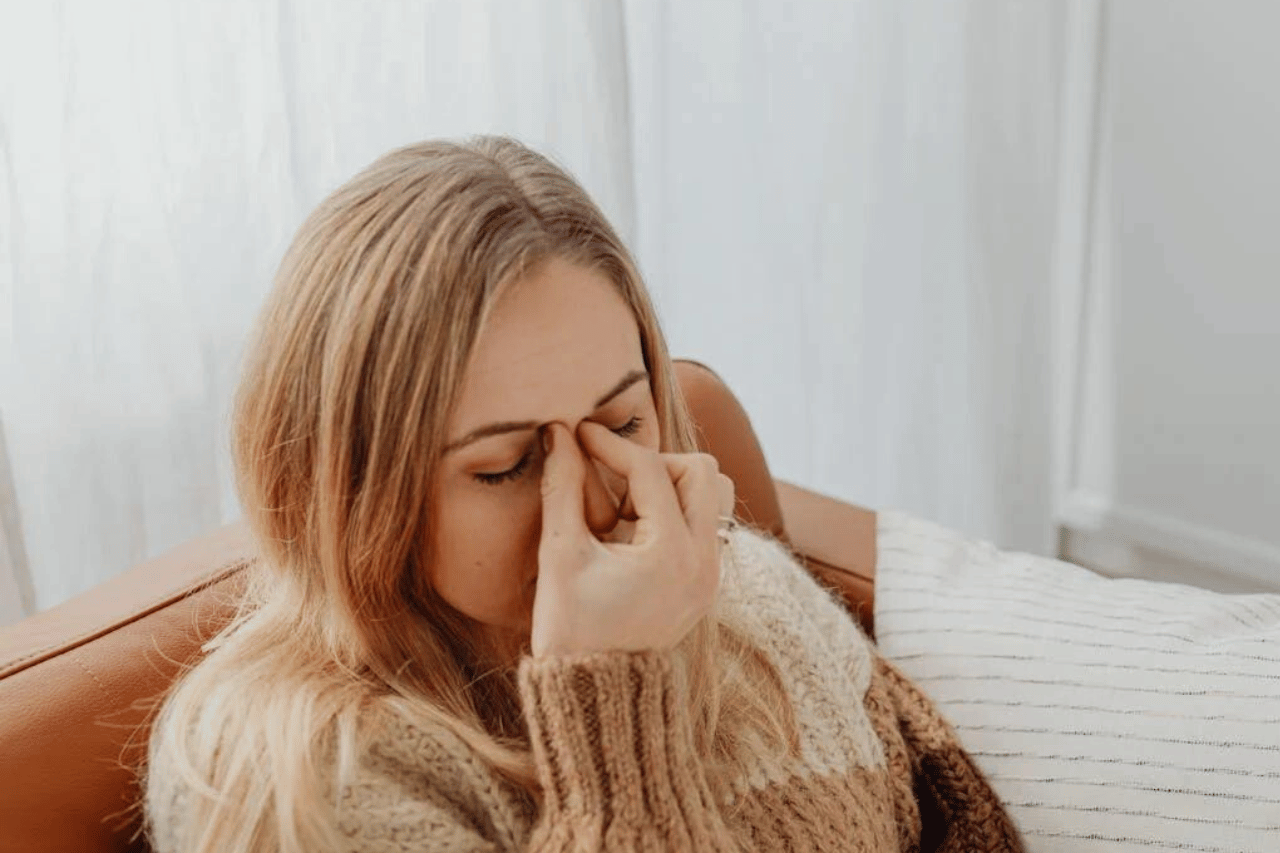 Kvinna med näsblod av stress som håller mot näsroten
