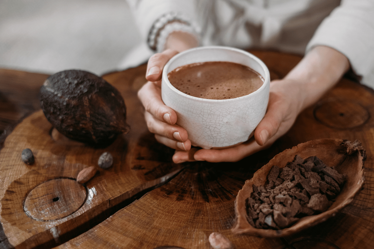 Person som håller i en kopp fylld med chokladdryck av superfoods som kakaobönor och chaga.