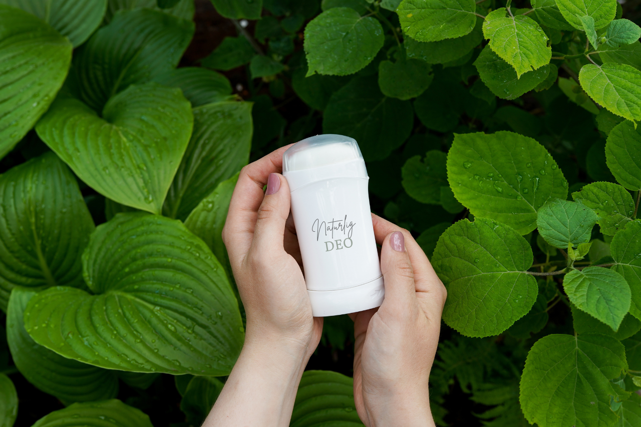 En kvinna håller en naturlig deo utan aluminium i sina händer med naturen som bakgrund.